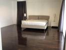 Spacious bedroom with a large bed, hardwood floors, and elegant drapes