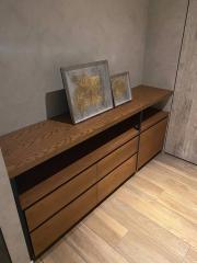 Modern wooden sideboard with artwork in a dimly lit interior space