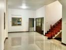 Spacious living room with glossy tiled flooring and staircase