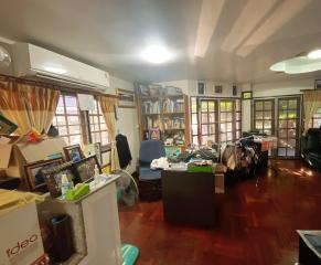 Spacious living room with clutter indicating moving or renovation, hardwood floors, and ample natural light