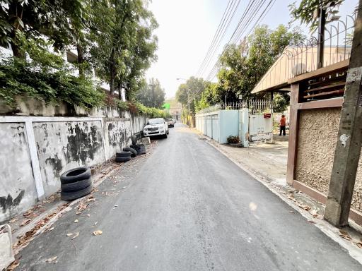 Paved street with parked cars and surrounding fences