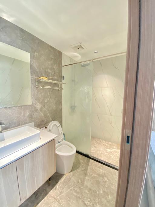 Modern bathroom interior with marble tiles and glass shower enclosure