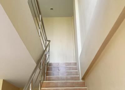 Staircase with metal handrail and tiled steps in a modern home.