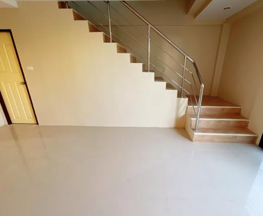 Bright and spacious staircase area leading to the upper level with wooden steps and metal railing