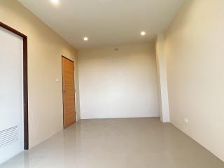 Spacious empty room with beige walls and tile flooring