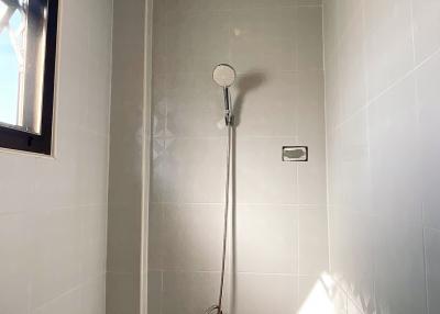 Modern bathroom with clean white tiles and a wall-mounted shower head