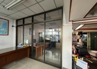 Spacious office space with glass partition and modern furniture