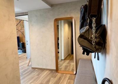 Modern hallway with wooden floors, mirror, and coat hooks