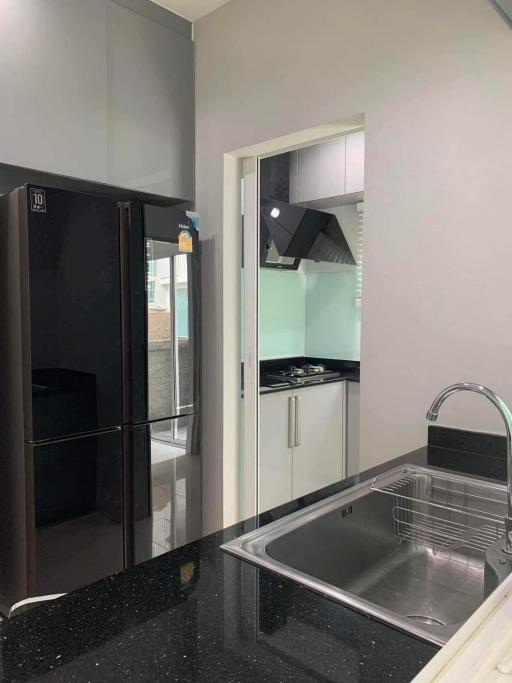 Modern kitchen interior with black refrigerator, stainless steel sink, and built-in appliances