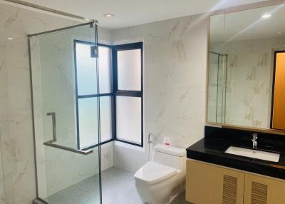 Modern bathroom with glass shower enclosure and marble walls