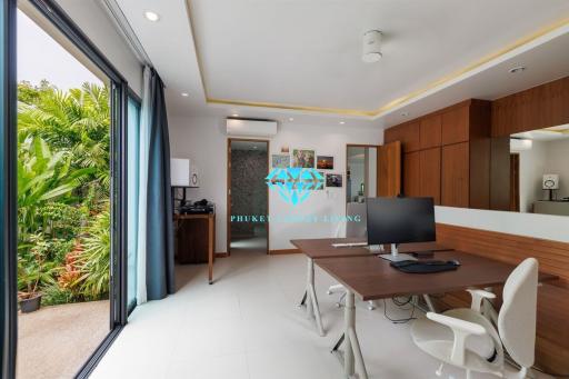 Modern home office with large desk, ergonomic chairs, and a view to the garden