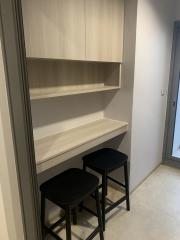 Compact built-in workspace with shelves and stools in a narrow room
