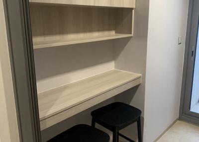 Compact built-in workspace with shelves and stools in a narrow room