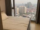 Cozy bedroom with a large window overlooking the city skyline