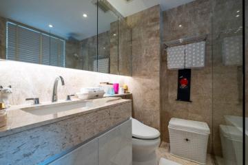 Modern bathroom interior with marble tiles, large mirror, and well-lit vanity area