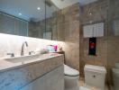 Modern bathroom interior with marble tiles, large mirror, and well-lit vanity area