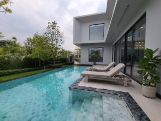 Modern house exterior with pool and lounging chairs