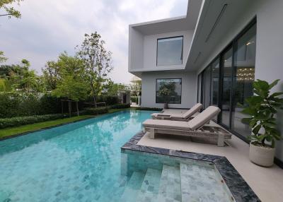 Modern house exterior with pool and lounging chairs