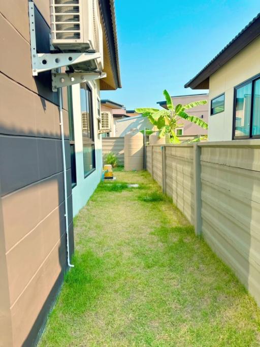 Lawn with outdoor unit and partial view of a house exterior