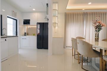 Modern kitchen with white cabinets, stainless steel appliances, and an adjacent elegant dining area with decorative flowers