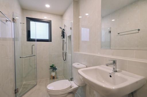 Modern bathroom interior with glass shower, toilet, sink, and mirror