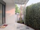 Cozy patio area with sliding glass door and privacy hedge