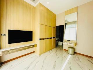 Spacious modern living room with wall-mounted TV and bright wooden paneling