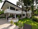 Spacious white two-story house with balconies, surrounded by lush greenery