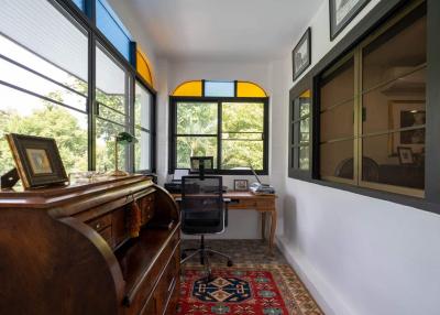 Bright home office with large windows and antique desk