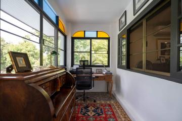 Bright home office with large windows and antique desk