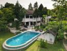 Aerial view of a luxurious house with a swimming pool and a well-maintained garden