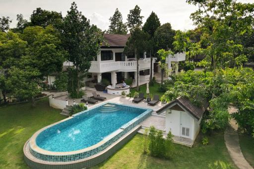 Aerial view of a luxurious house with a swimming pool and a well-maintained garden