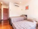 Spacious bedroom with twin beds, wooden furniture, and air conditioning