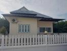 Single-story residential home with a white picket fence and an air conditioning unit