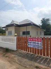 White single-story house with fence and for sale sign