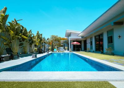 Elegant outdoor swimming pool with adjacent lounge area in a sunny backyard