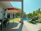 Spacious backyard with a swimming pool, patio area, and lush greenery