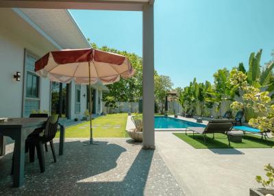 Spacious backyard with a swimming pool, patio area, and lush greenery