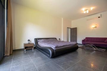 Modern bedroom with black bed frame and contrasting purple sofa