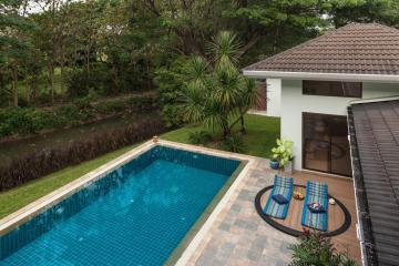 Cozy outdoor space with pool and seating area surrounded by lush greenery