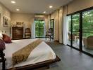 Spacious bedroom with a king-sized bed, large windows, and balcony access overlooking greenery