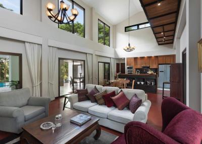 Spacious, high-ceiling living room with abundant natural light, modern furniture, and pool view