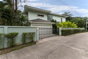 Elegant two-story house with a gated fence and lush greenery