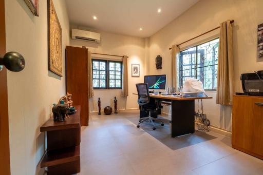 Home office with computer desk, chair, and multiple windows