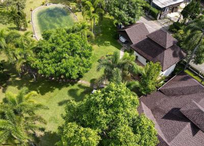 Aerial view of a residential property with lush landscaping and a swimming pool