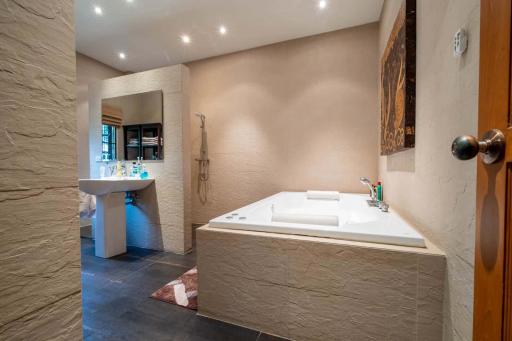 Spacious modern bathroom with jacuzzi and stone accents