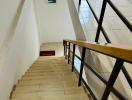 Brightly lit staircase with wooden handrail and ceramic tiles