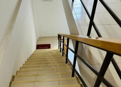 Brightly lit staircase with wooden handrail and ceramic tiles
