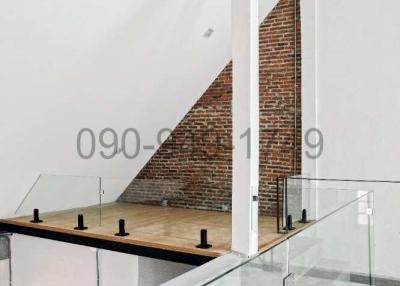 Modern interior mezzanine with exposed brick wall and glass balustrade