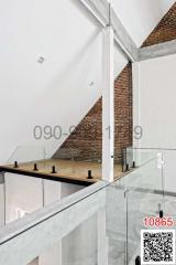 Modern interior mezzanine with exposed brick wall and glass balustrade